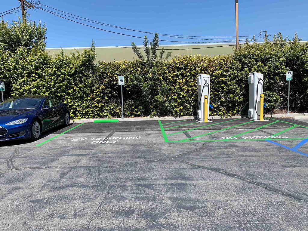 Two DCFC chargers and a blue Tesla